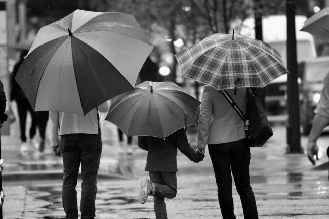 two adults and a child with umbrellas in the rain