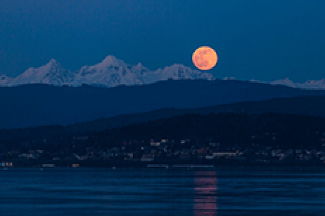 pink super moon rising over snow capped mountains