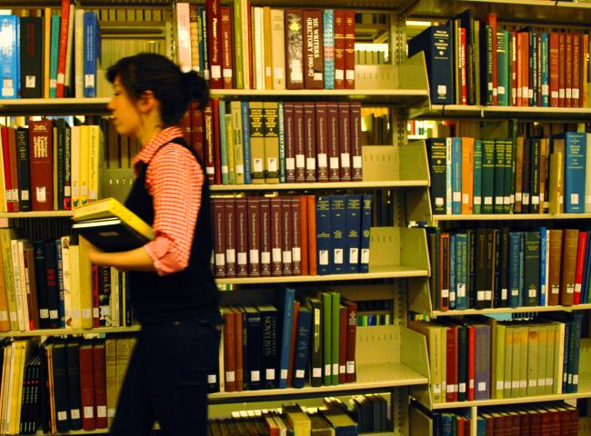 woman walking in front of shelves of books