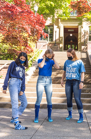 three student show off their blue socks to celebrate Give Day