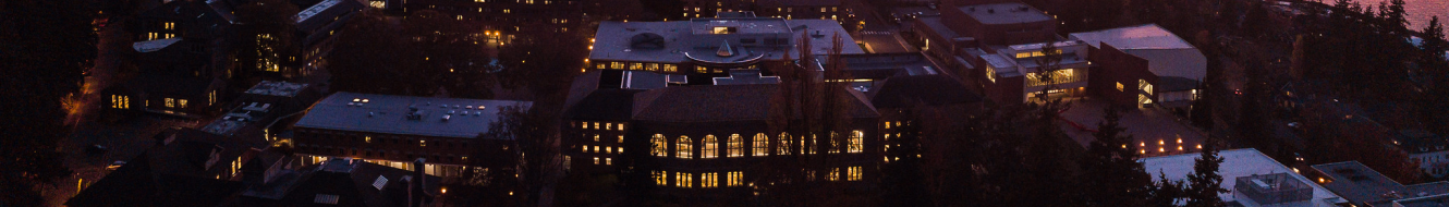 aerial view of lit up campus buildings against water colored pink by sunset